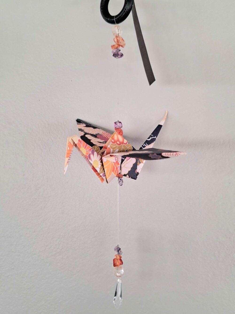 origami crane strung together with various beads to create a hanging mobile or suncatcher